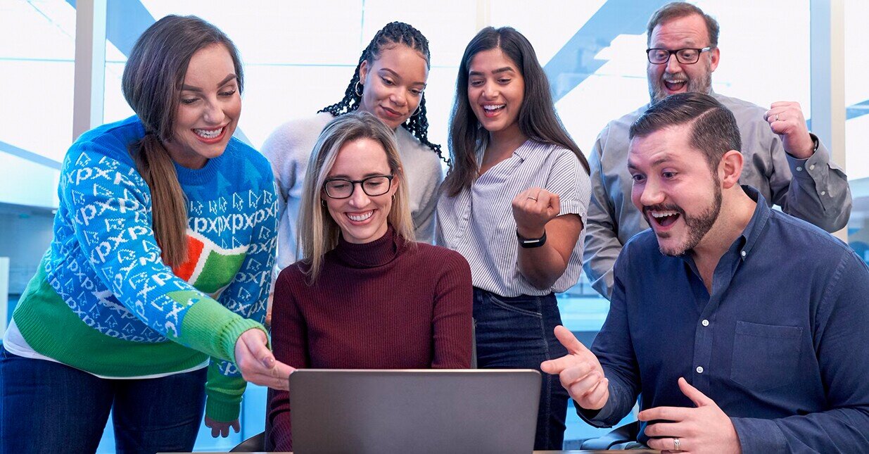 grupo de pessoas felizes a ver um ecr&atilde; de port&aacute;til
