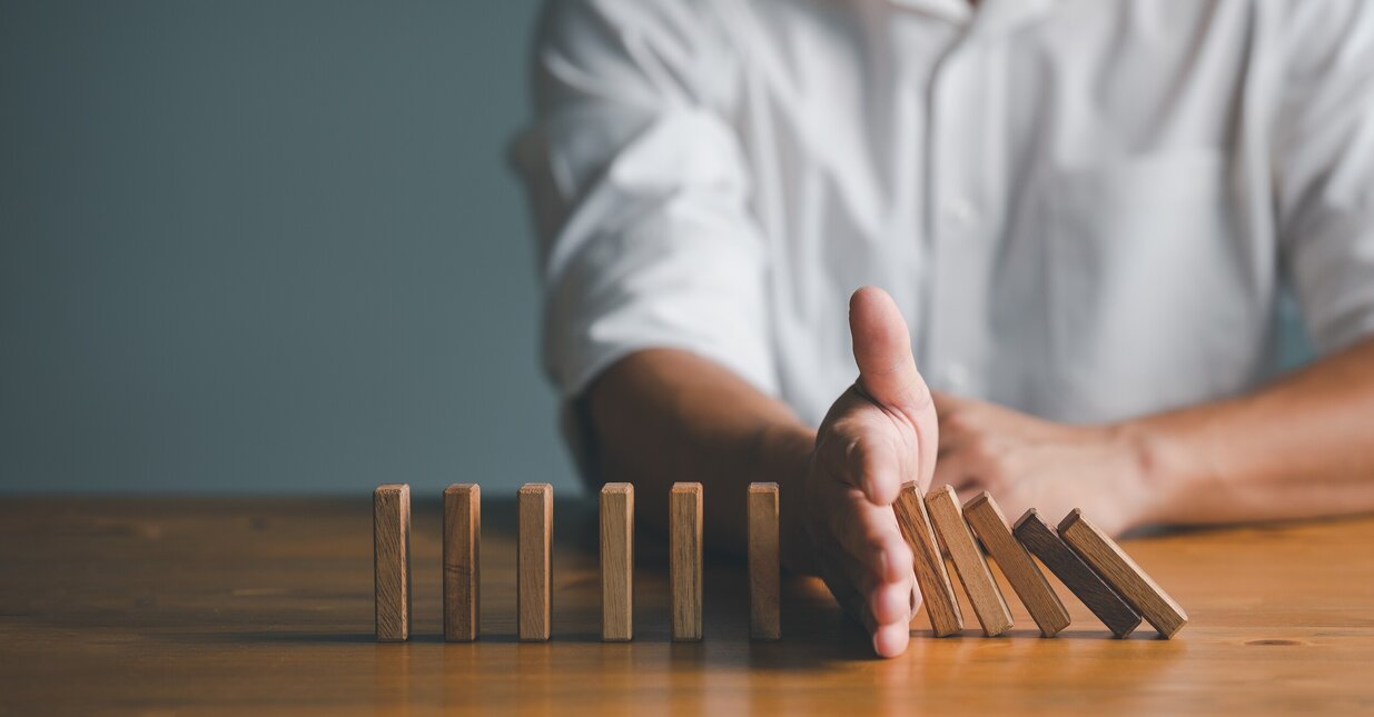 Pessoa a parar um domin&oacute; que ia cair